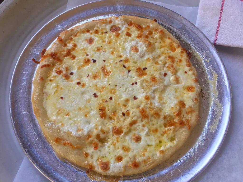 A freshly baked cheese pizza with a golden crust and melted cheese, topped with a sprinkle of red pepper flakes.