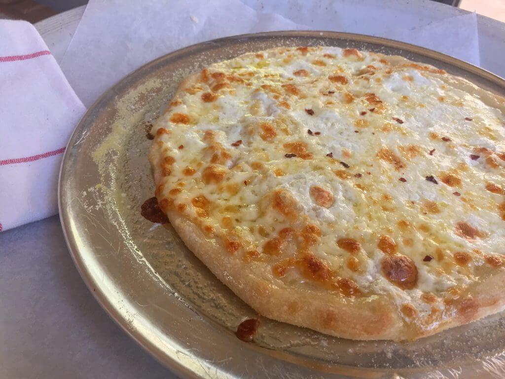 A close-up of a freshly baked cheese pizza with a golden crust on a baking tray.