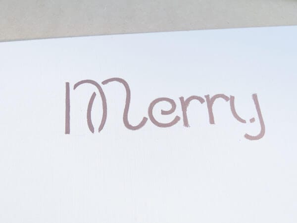 The word "Merry" is handwritten in a casual, script-like font on a white surface.