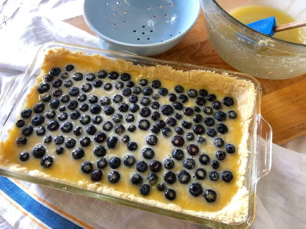 A glass baking dish filled with unbaked lemon filling and fresh blueberries.