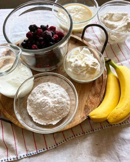 A collection of ingredients for making a dessert, arranged on a wooden tray.