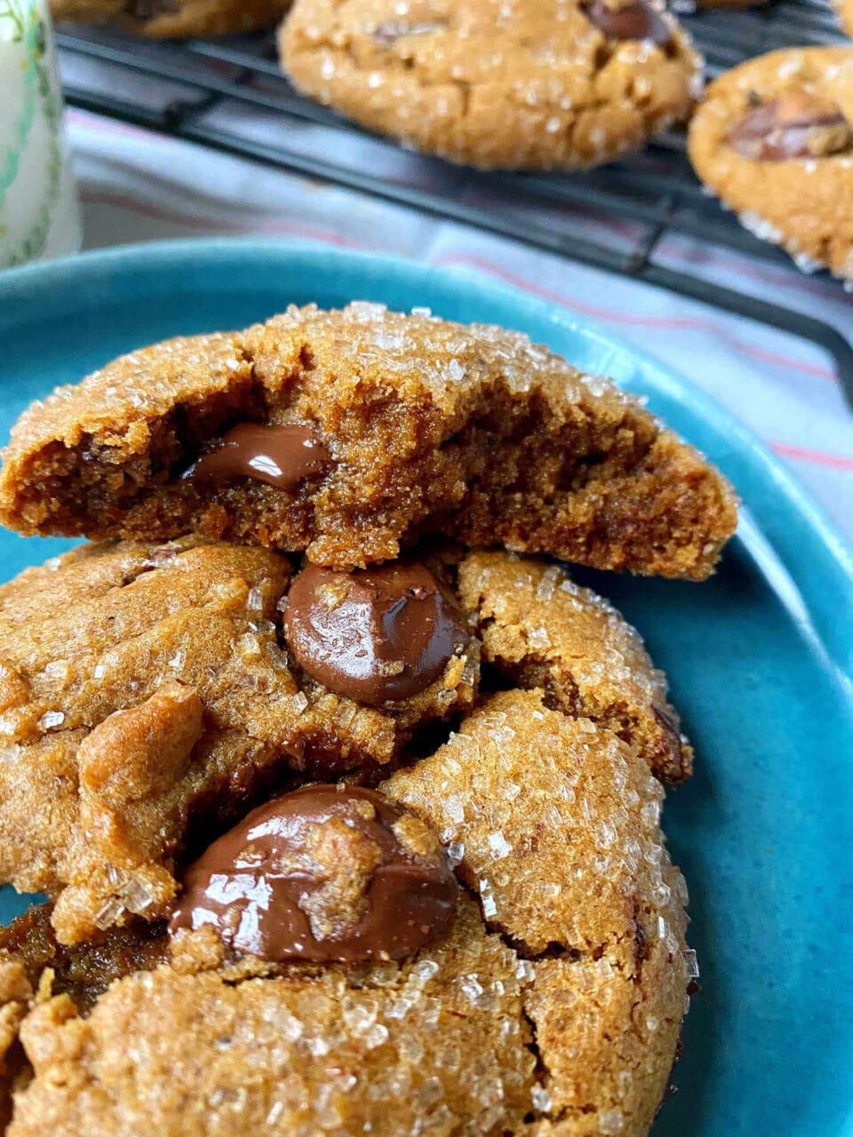 Close-up of a freshly baked chocolate chip cookie on a blue plate, with melty chocolate chips and a sprinkling of sugar on top.