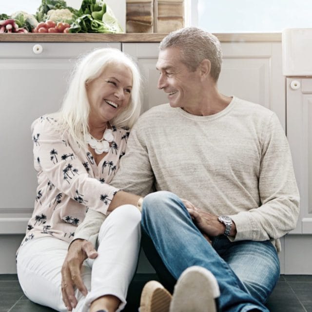 Two people sitting happily on the kitchen floor.