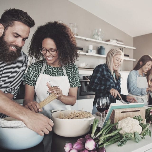 A group of people making a meal in a kitchen.