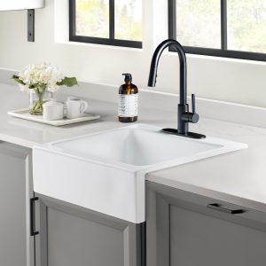 A glossy white rectangular Quick-Fit® drop-in farmhouse sink made in fireclay with a modern black faucet set in solid surface gray countertop and dark gray cabinets.