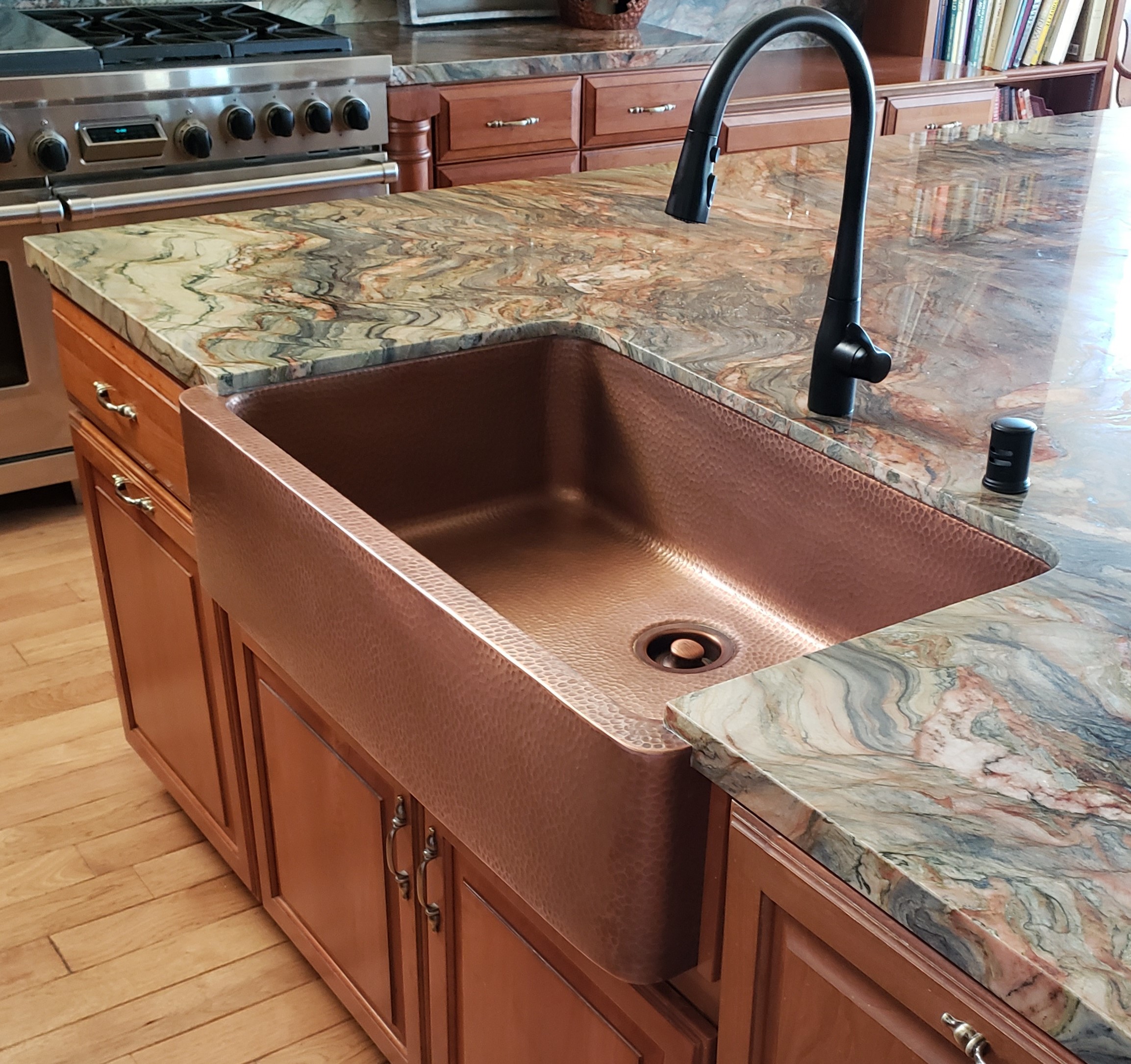 A copper rectangular undermount sink with green marble countertops