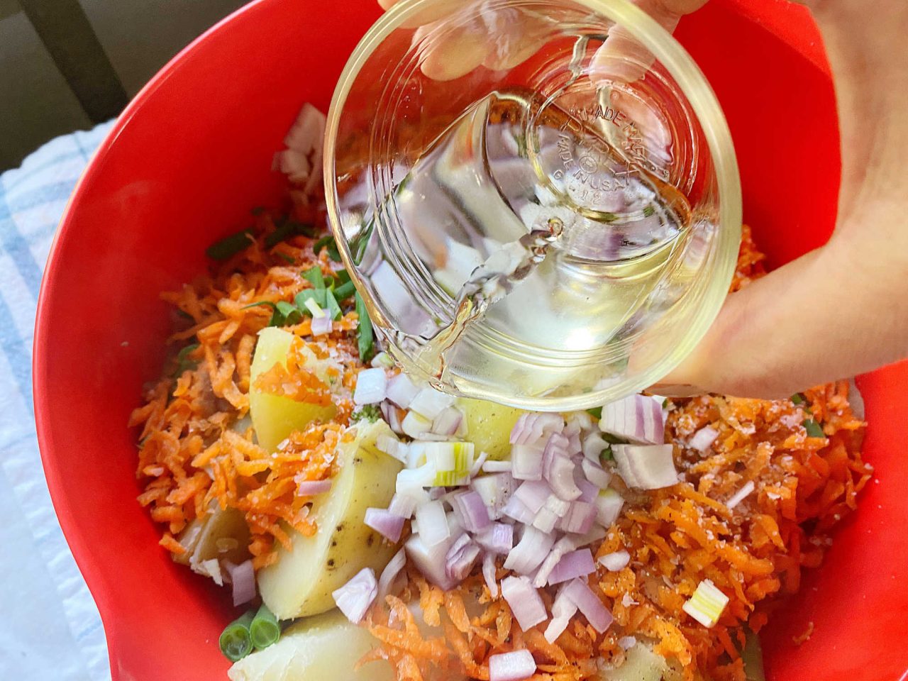 Adding ingredients to bowl for warm veggies potato salad