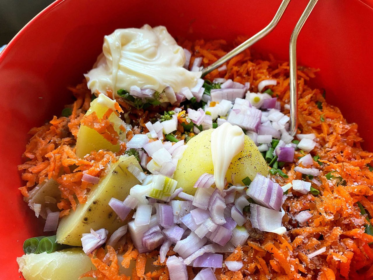 Warm veggies potato salad in a bowl being mixed up