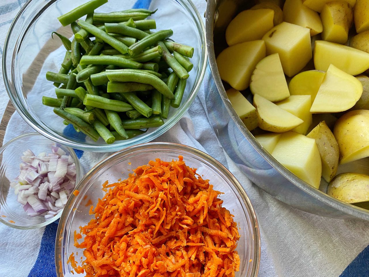 Warm veggies potato salad ingredients in a bowls