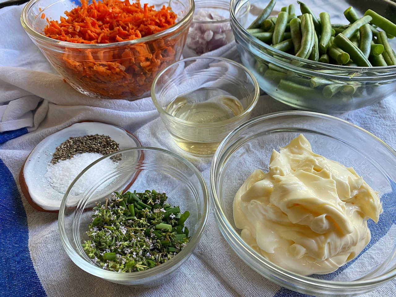 Warm veggies potato salad ingredients in a bowls on a kitchen counter covered with towels