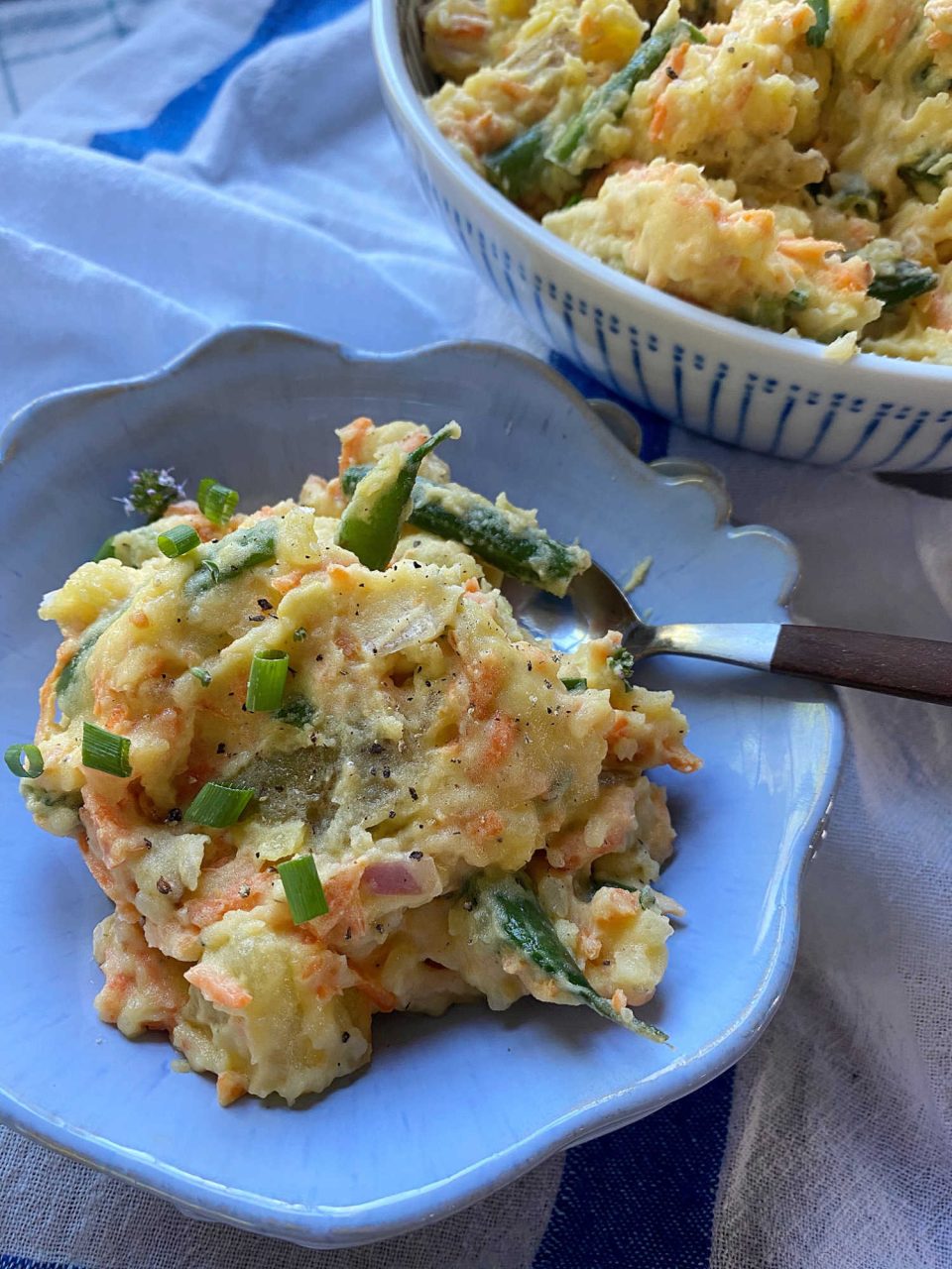 Warm veggies potato salad in a bowl with spoon