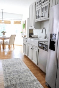 a white fireclay kitchen sink with a stainless steel faucet in a white painted kitchen