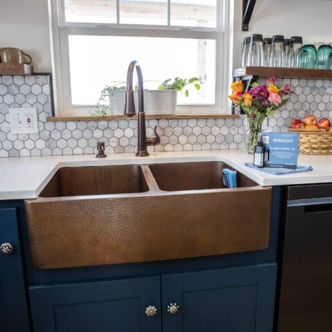 A copper kitchen sink with a Copper Care IQ kit sitting on the countertop
