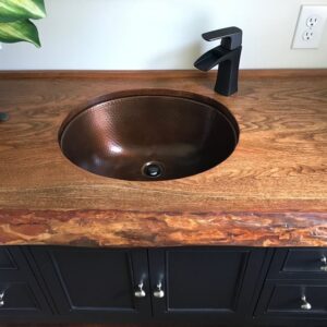 A hand hammered copper undermount bathroom sink.