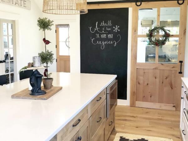 Bright kitchen with a large island, chalkboard wall, sliding barn door, and festive decor.