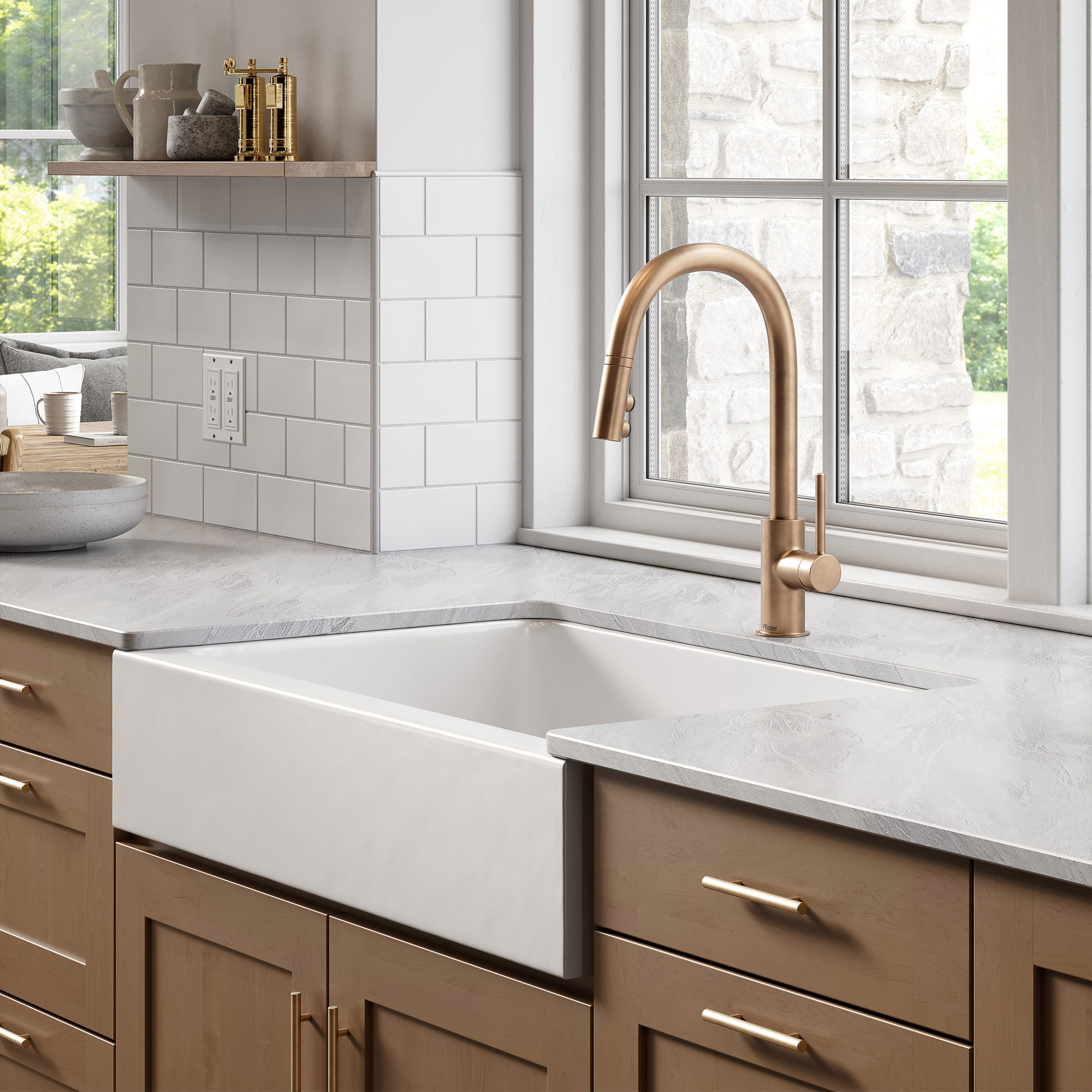 White farmhouse kitchen sink with gold faucet in front of window
